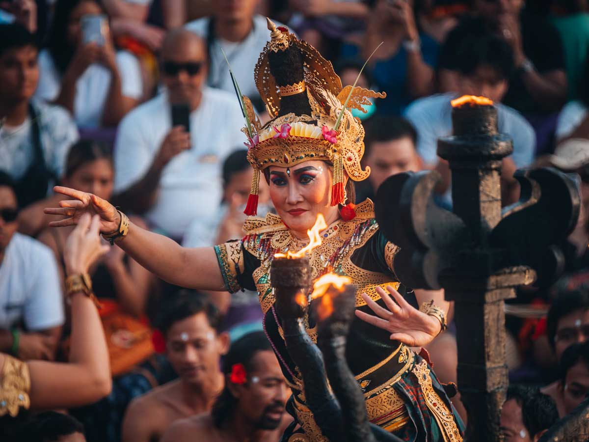 Hanuman leaping above the seated Kecak chanters beside a lit fire lamp