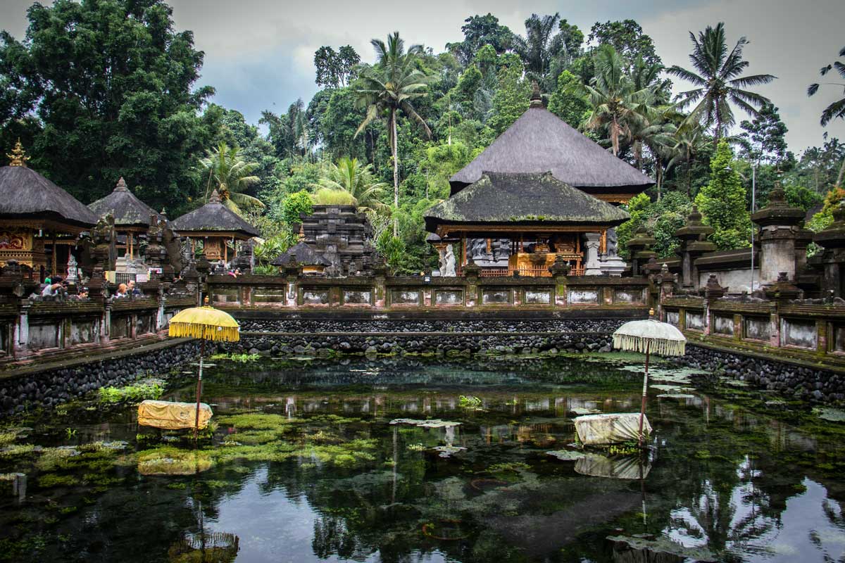 Spring pool with thatched shrines and ceremonial umbrellas at Tirta Empul